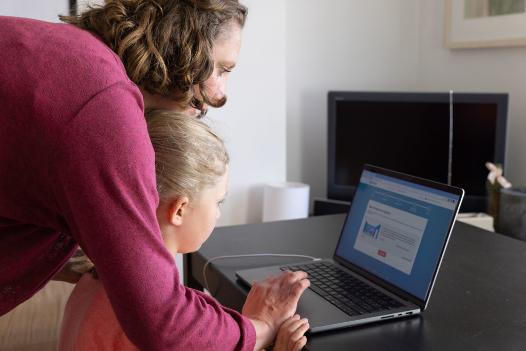 Woman looking at laptop screen with child